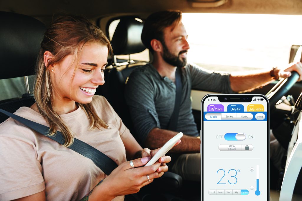 Image of positive young amazing loving couple outdoors at the beach in car. Woman using mobile phone.